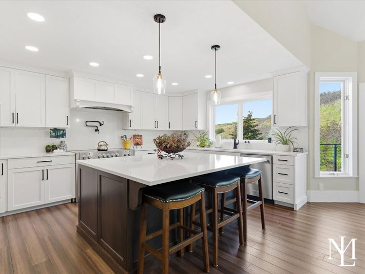 White gourmet kitchen with oversized island, quartz countertops, and hillside views in updated Layton Utah home.