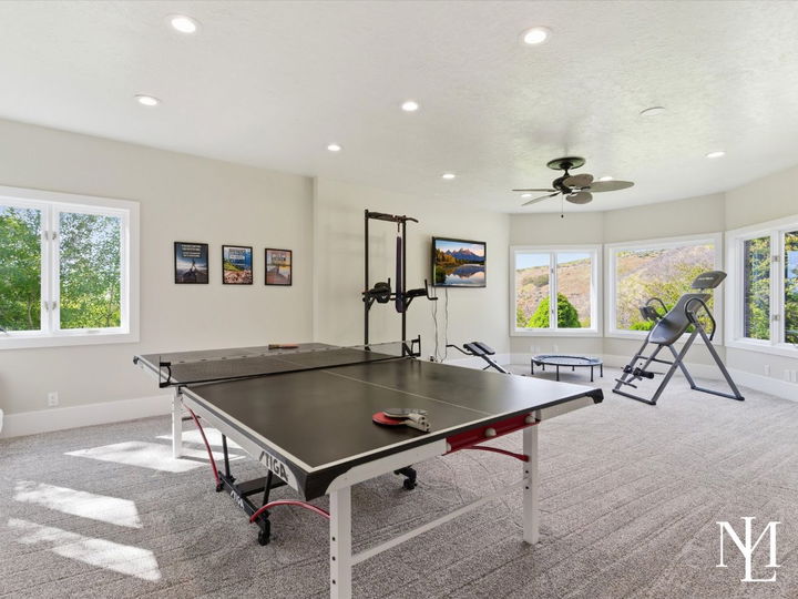 Large recreation room with ping pong table, fitness space, and oversized windows in renovated Layton Utah home.