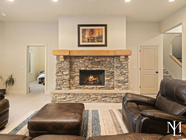 Living room in Trapper’s Ridge home with stone fireplace, leather seating, and warm mountain lodge finishes