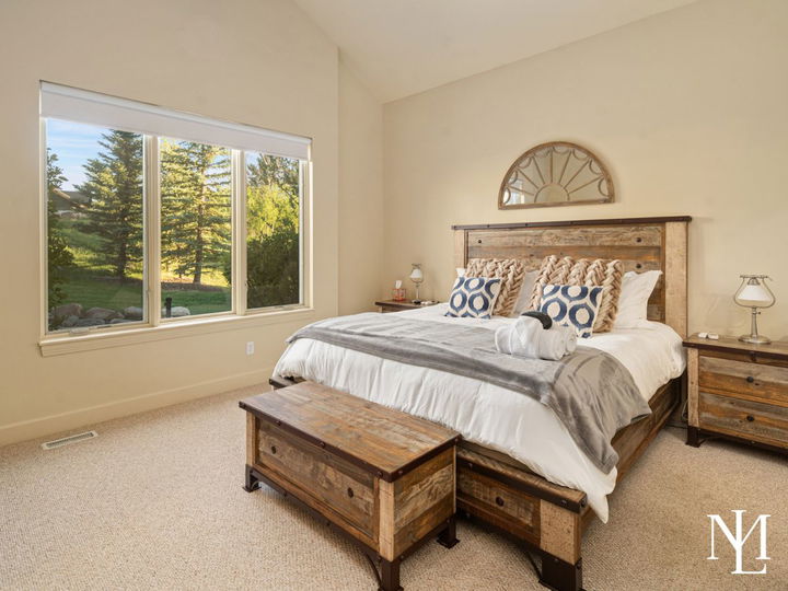 Primary bedroom in furnished Eden Utah home with rustic wood furniture, large window, and mountain retreat style