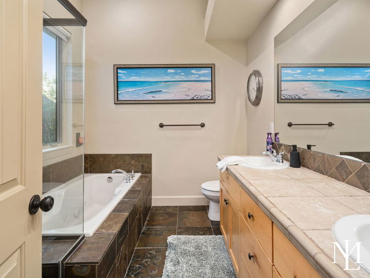 Primary bathroom in Eden mountain home with jetted tub, tile surround, wood vanity, and glass shower