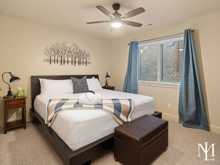 Furnished bedroom in Eden Utah vacation home with ceiling fan, blue curtains, and turnkey mountain lodging setup