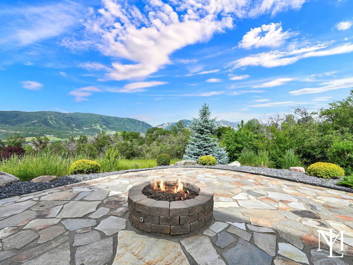 Stone patio in Eden Utah with fire pit, professional landscaping, and views toward Nordic Valley and Ogden Valley mountains