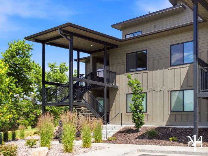Exterior of The Pointe at Wolf Creek condo building with covered stairs, landscaping, and mountain view