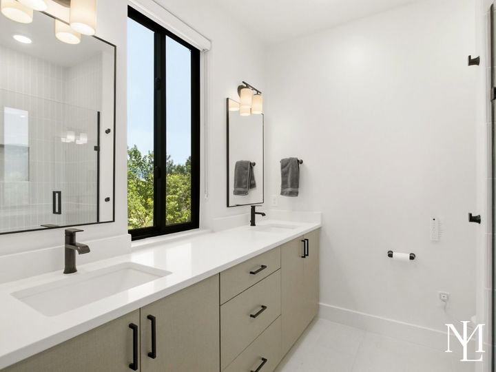 Bathroom with double vanity, black fixtures, large mirror, and walk-in shower.