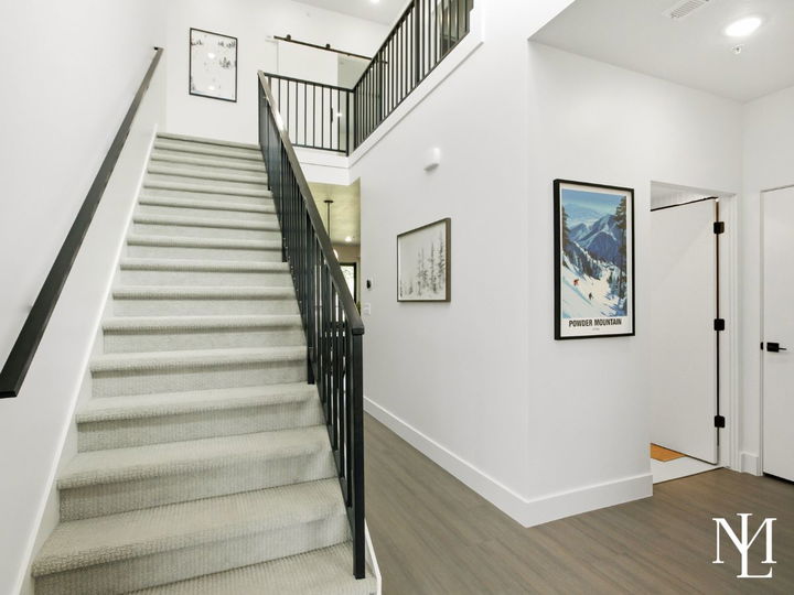 Interior stairway with black railing, mountain artwork, and modern white walls.