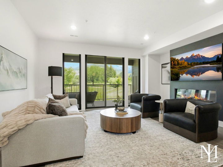 Living room with fireplace, large windows, balcony access, and views of the creek and golf course.