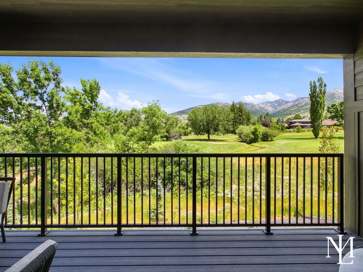 Covered balcony overlooking Wolf Creek Golf Course, mature trees, and surrounding Ogden Valley mountains.