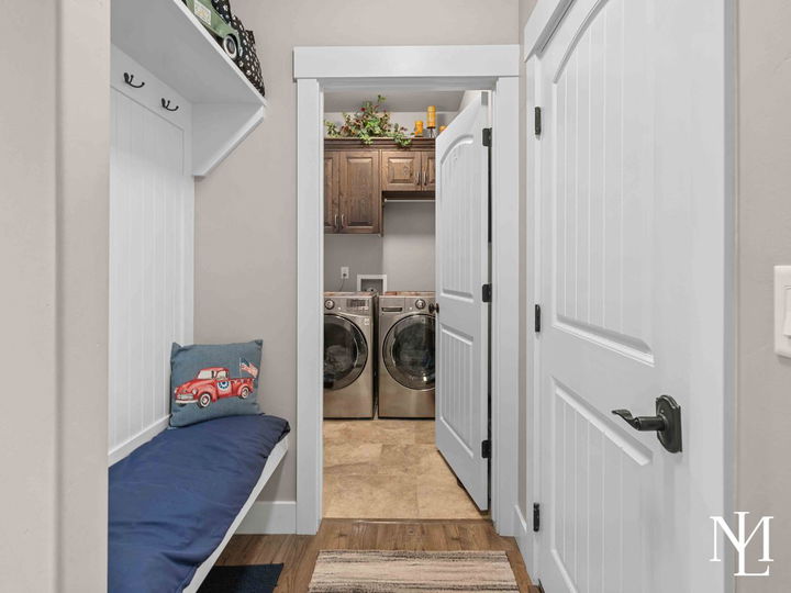 Mudroom entry with built-in bench and adjacent laundry room with upper cabinetry.