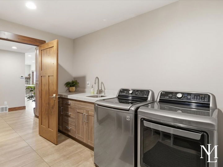 Laundry room with washer and dryer, sink, cabinetry, and tile flooring.