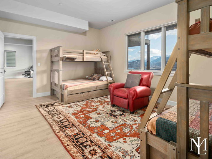 Bunk room with four bunks, a large rug, and red chair in between the beds