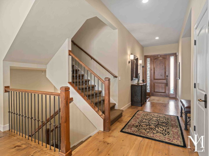 Welcoming entryway with warm wood accents and a set of stairs leading up and down