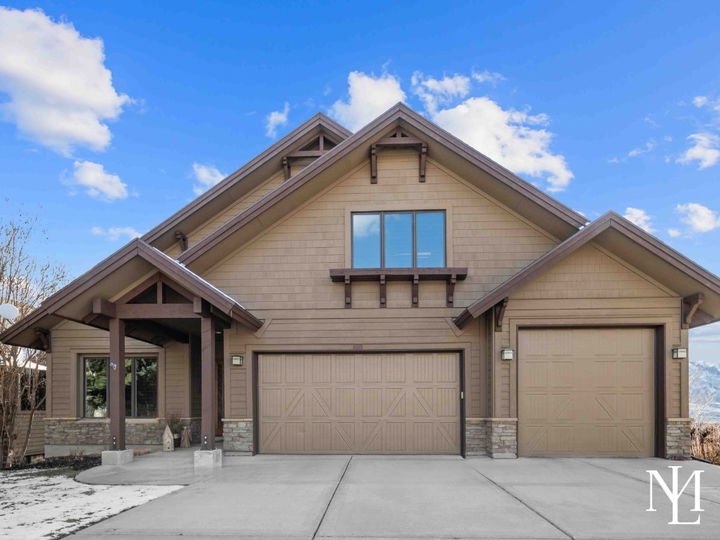 Luxury mountain home with 3 car garage and rustic accents with blue sky behind it