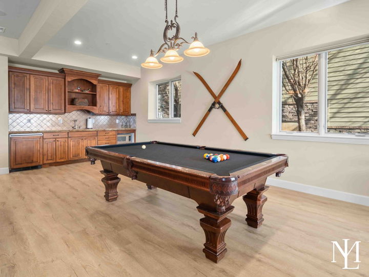Walk-out basement with kitchenette, large pool table, and decorative vintage skis on the wall