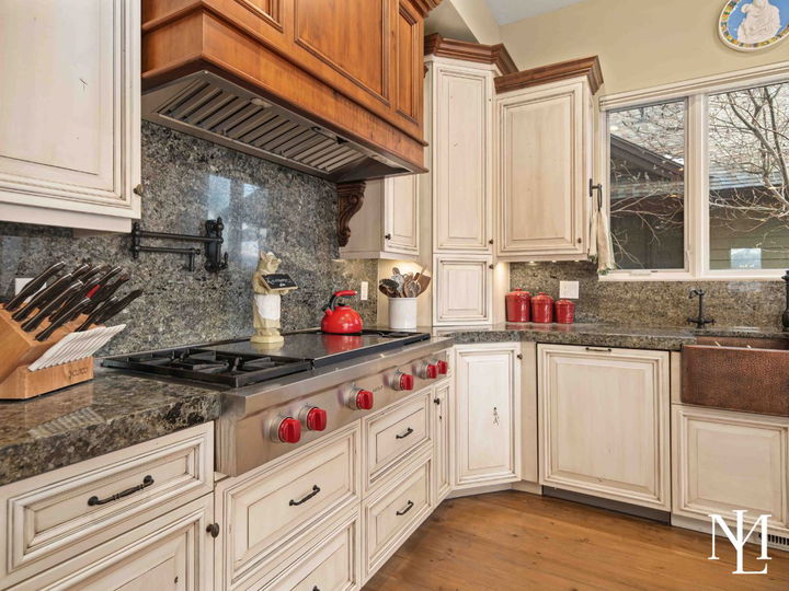 Gourmet kitchen with hidden dishwasher, copper sink, grey granite counters, and plentiful cabinet storage