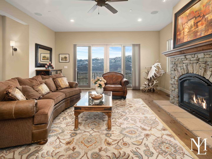 Rustic living room with stone fireplace, a couch, glass coffee table, and sliding doors out to balcony