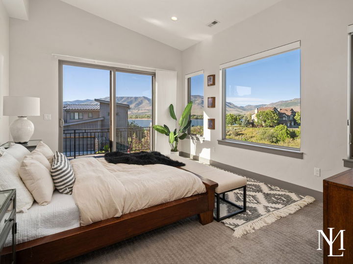 Bedroom with balcony access, large windows, and views of Pineview Reservoir and surrounding mountains.