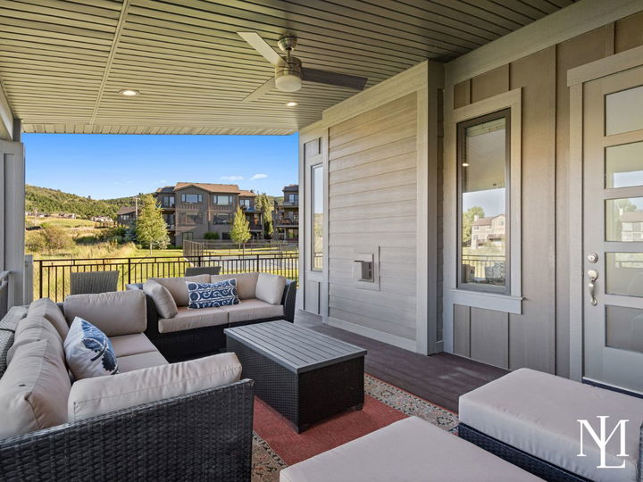 Covered deck with outdoor lounge seating and views of the Edgewater community lawn.