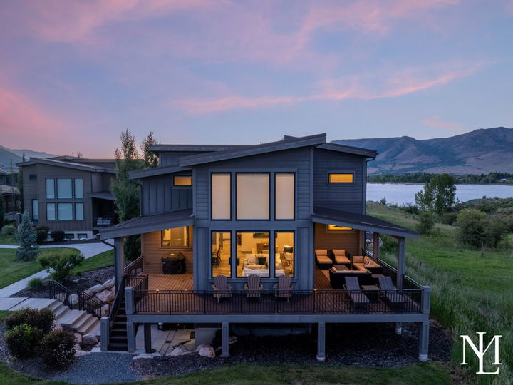 Rear exterior of a Huntsville home with covered decks, outdoor seating, and Pineview Reservoir views.