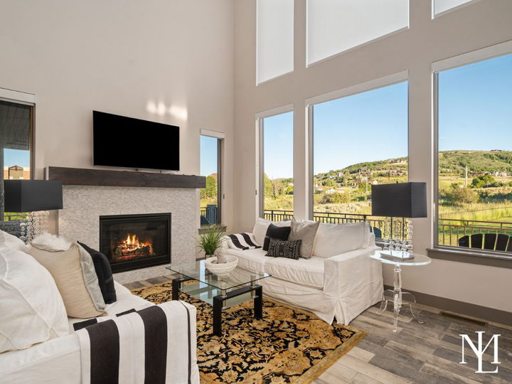 Bright living room with vaulted ceilings, fireplace, large windows, and mountain views.