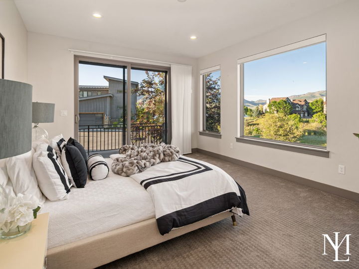 Bedroom with private balcony access, large windows, and mountain community views.