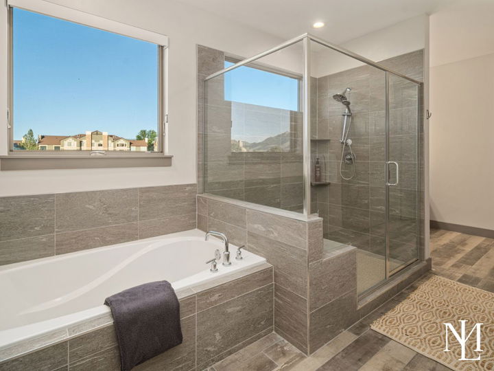 Primary bathroom with soaking tub, glass shower, tile surround, and mountain views.