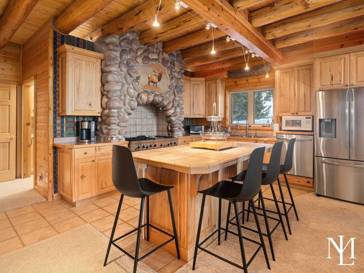 Rustic kitchen with stone range hood, large island, bar seating, and stainless appliances.