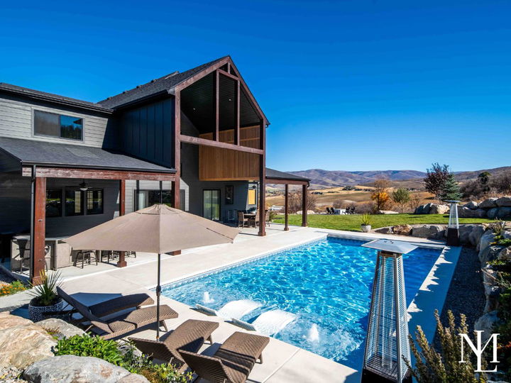 Backyard with in-ground swimming pool, covered patio, and mountain views.