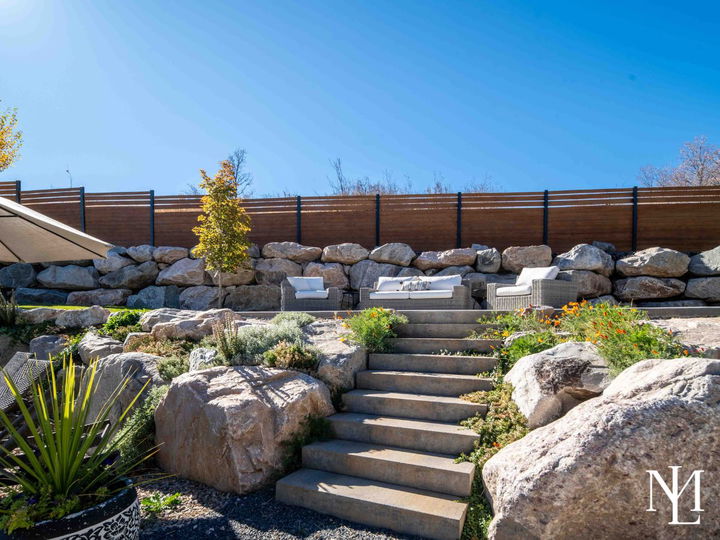 Terraced backyard landscaping with stone retaining walls, garden beds, and outdoor seating area.