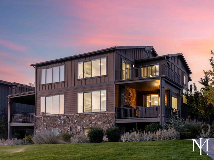 Exterior view of a furnished Huntsville townhome at sunset with stone accents, covered balconies, manicured lawn, and mountain-resort styling.