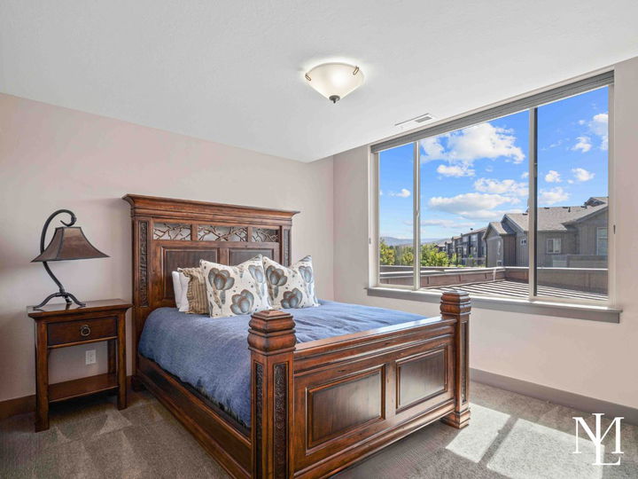 Guest bedroom with carved wood bed, large window, and views of the surrounding Huntsville community.