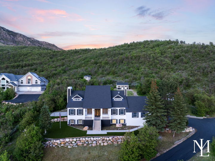 Aerial view of a private Huntsville home set against wooded hillside terrain with mountain views and a landscaped front yard.