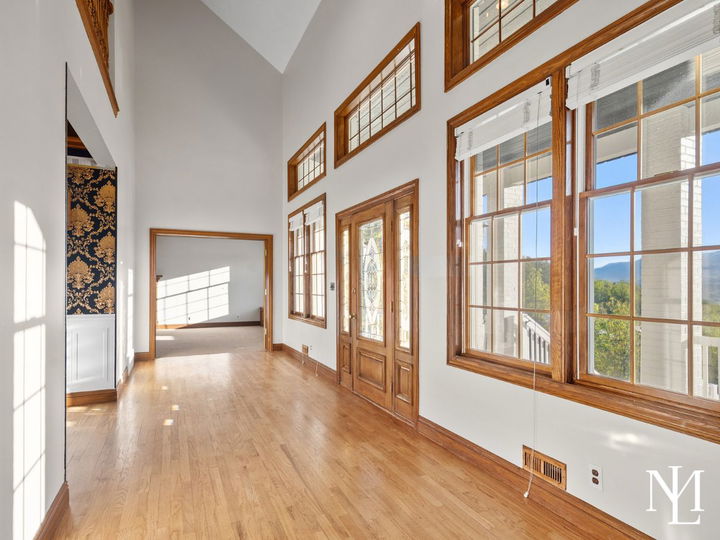 Bright vaulted entryway with hardwood floors, wood-trimmed windows, and mountain views from the front of the home.