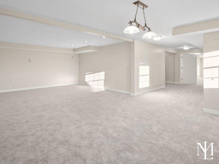Finished lower-level living area with soft carpet, neutral walls, and flexible space for entertaining or recreation.