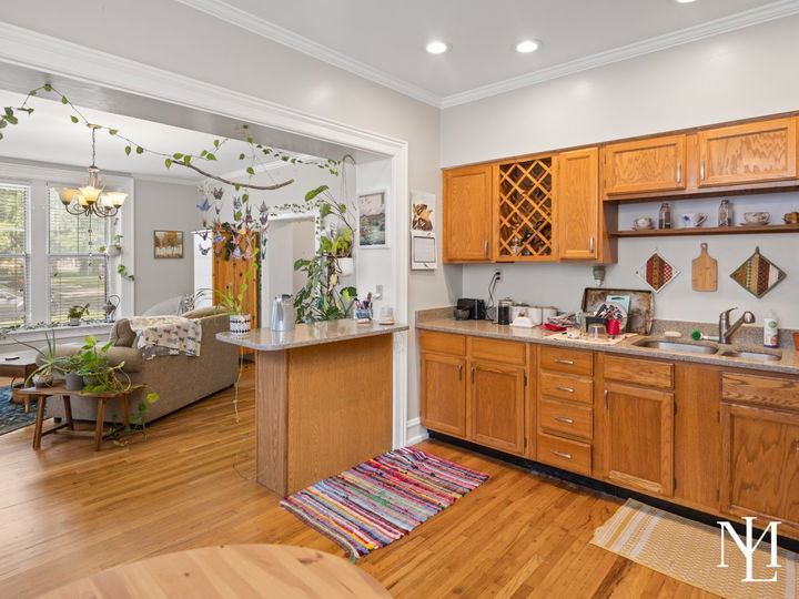 Kitchen with wood cabinetry, hardwood floors, open pass-through, and adjoining living space