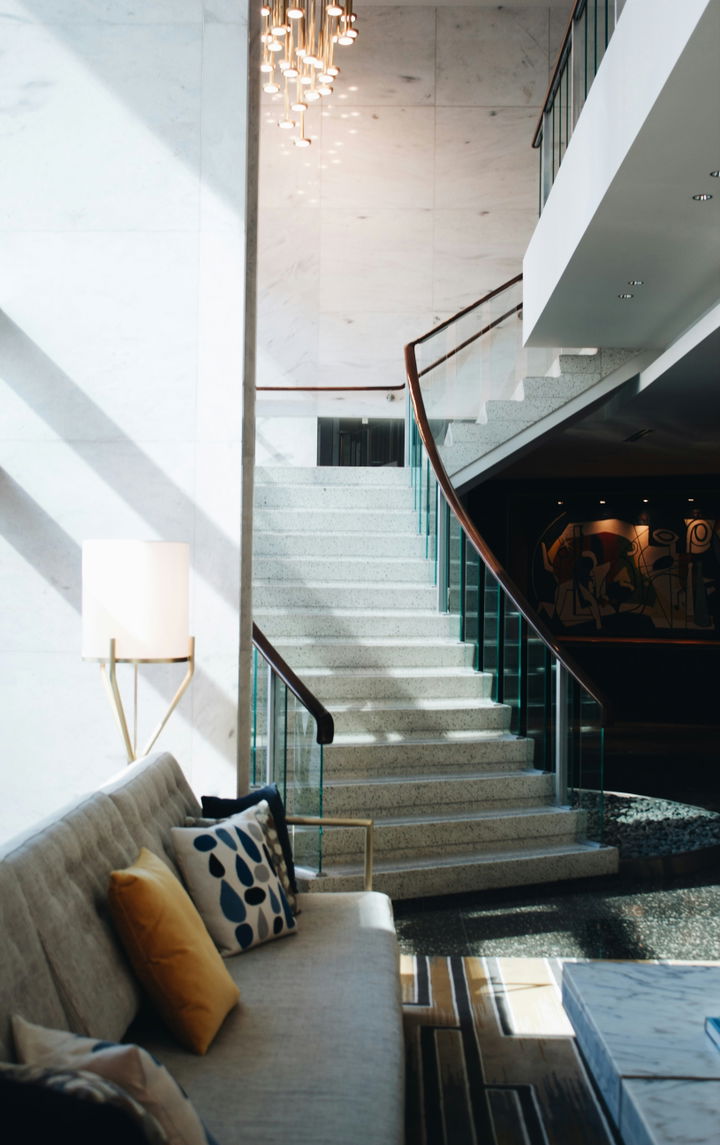 A combination of quality stones are showcased in a staircase and wall, in the forefront is a couch and there are many textile patterns.