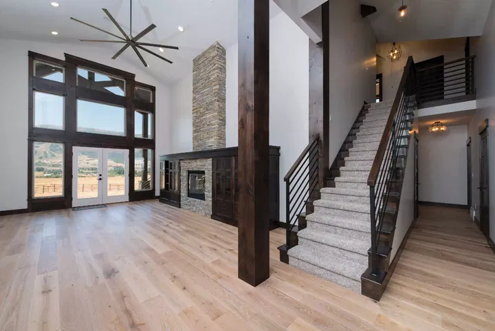 An Empty Great Room with a Large Ceiling Fan and Stairway