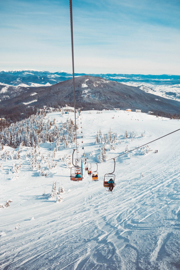 View from a chairlift of a skied out slope and oher people on the chairlift.