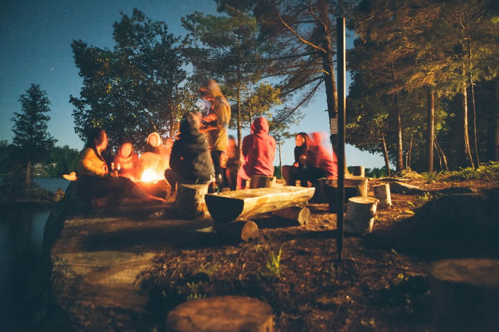 Campers gathered around a fire on a starry night