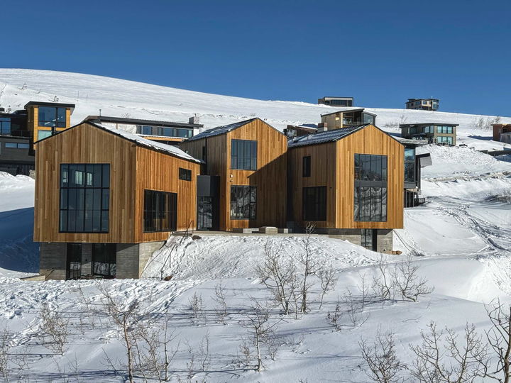 Luxury cabins with expansive windows at Powder Mountain surrounded by snow and other luxury homes